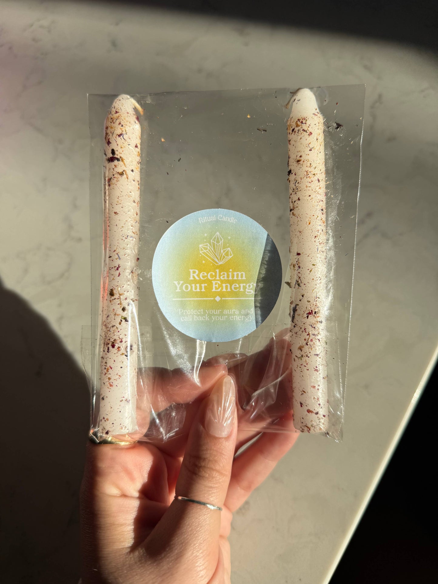 Two cylindrical products in a clear plastic bag with 'Reclaim Your Energy' label held by a hand.
